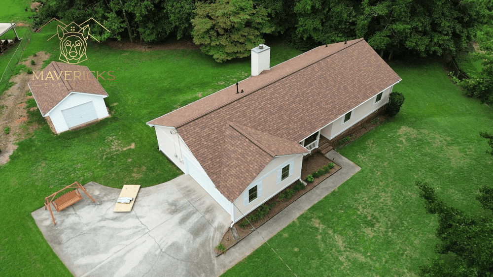 Aerial view of a ranch home and detached garage with new brown shingle roofs