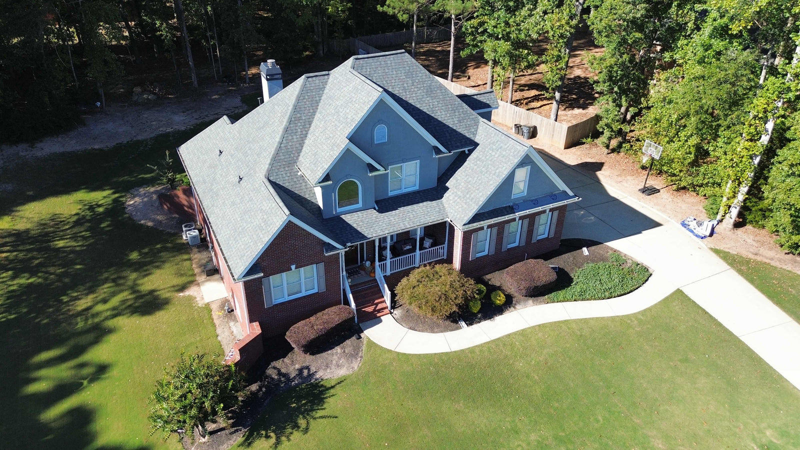Aerial view of a two-story home with a new gray shingle roof